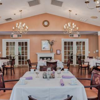 An elegant dining room with neatly arranged tables and chandeliers hanging from the ceiling.