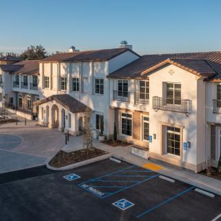 A modern residential building with a spacious parking lot on a clear day.