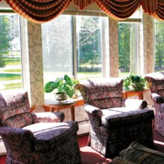 A cozy living room with patterned chairs, large windows, and sunlight streaming in.