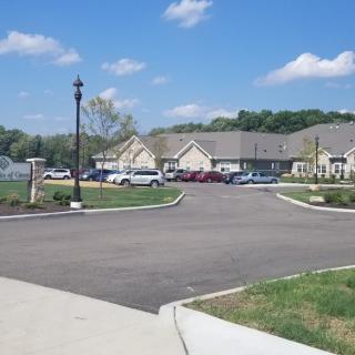 A peaceful suburban residential area with single-story buildings and a parking lot filled with cars under a bright blue sky.