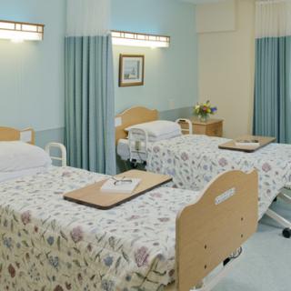 A hospital room with two beds separated by privacy curtains.