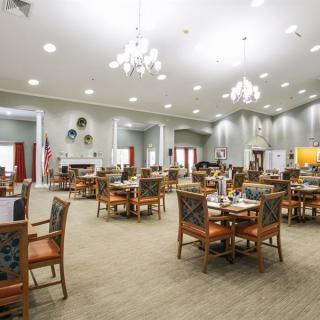 Spacious and elegantly designed dining area with multiple tables and chairs under chandeliers.