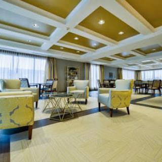 A spacious, elegantly designed lounge area with modern furniture and large windows.