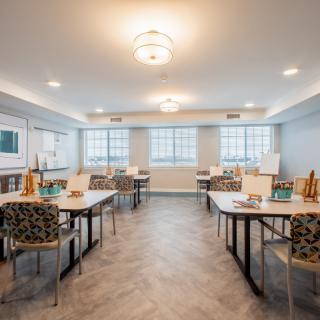 A well-lit classroom with tables and chairs arranged neatly, equipped with art supplies.