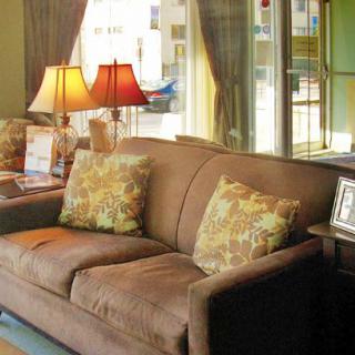 A cozy living room with a brown sofa, decorative cushions, and warm lighting from table lamps.