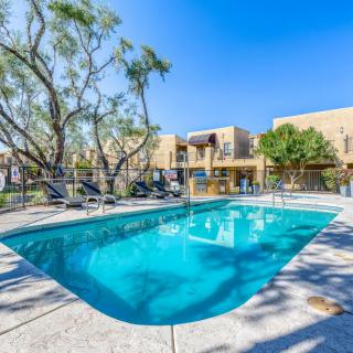 An inviting outdoor swimming pool surrounded by deck chairs and trees in an apartment complex under a clear blue sky.