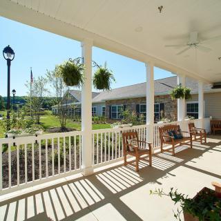 A sunny porch with benches overlooking a garden.
