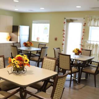 A cozy and bright dining room with neatly arranged tables and chairs, decorated with vibrant flowers.