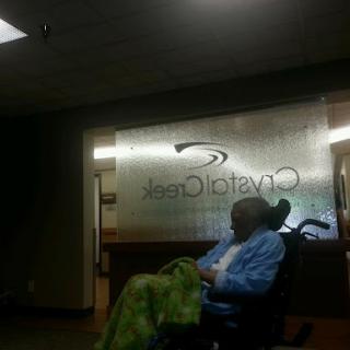A patient waiting in a medical facility, highlighted by the transparent signage in the background.