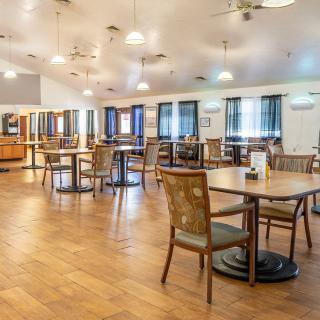 Spacious dining area with wooden flooring, tables, and chairs.