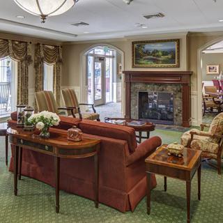A cozy living room with elegant furniture, featuring a fireplace and artwork.