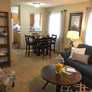 A cozy living room with an adjacent dining area, featuring a comfortable sofa and a coffee table adorned with a decorative centerpiece.