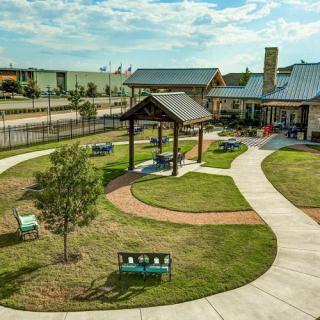 A scenic park with walking paths, benches, a pavilion, and a nearby building.