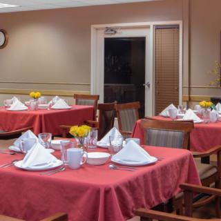An elegantly set dining area with red tablecloths and neatly arranged napkins.