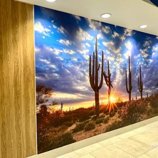 A stunning wall mural showcasing a picturesque desert sunset with silhouettes of cacti against a vibrant sky.