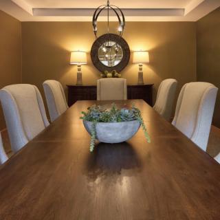 A well-decorated dining room featuring a wooden table, upholstered chairs, and ambient lighting.