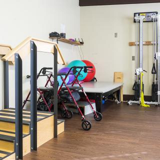A physical therapy room equipped with a staircase, walkers, exercise balls, and other rehabilitation equipment.