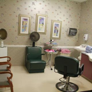 A cozy hair salon interior featuring a green chair, framed artwork, and salon equipment.