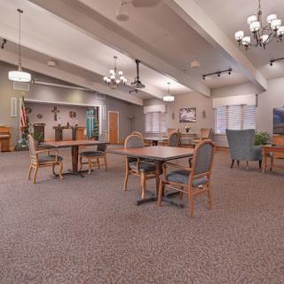 A spacious dining area with several tables and chairs, featuring large windows and elegant lighting fixtures.