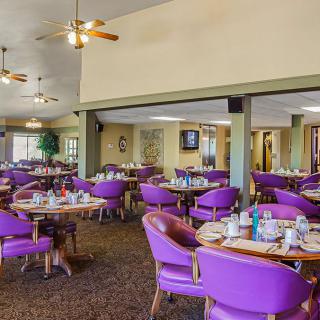 A spacious restaurant dining area with purple chairs and set tables.