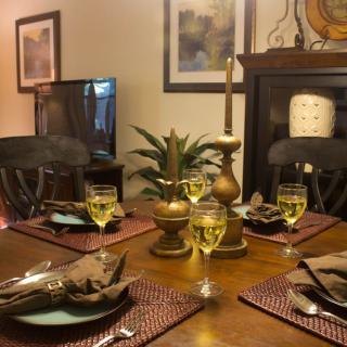 A warmly lit dining table set for a meal, featuring elegant candles and a decorative centerpiece.