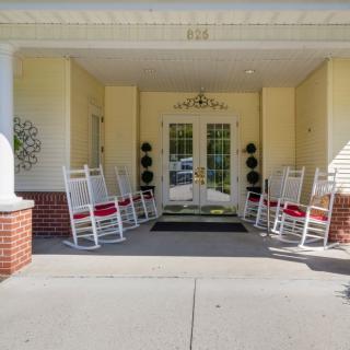 A welcoming entrance with rocking chairs lined up on a front porch.