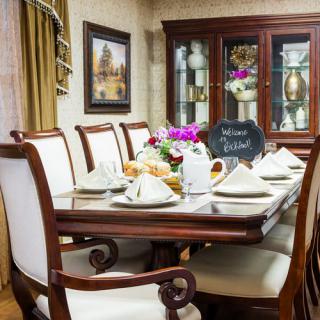 An elegantly set dining table with a floral centerpiece and neatly arranged table settings.