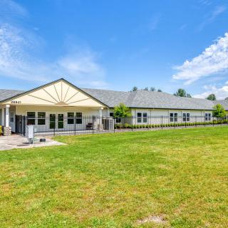A single-story building with a sloped roof set against a bright blue sky and surrounded by a grassy lawn.
