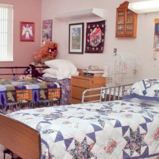 A cozy hospital room with twin beds adorned with colorful quilts and decorated walls.