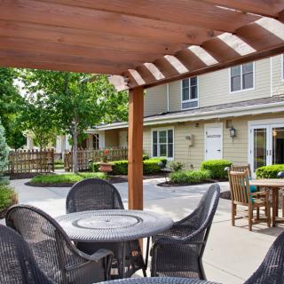 A peaceful outdoor patio with seating under a wooden pergola.