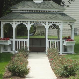 A charming white gazebo surrounded by a garden path with flower beds.