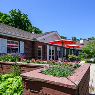 A charming outdoor patio area with red umbrellas and a well-maintained garden.