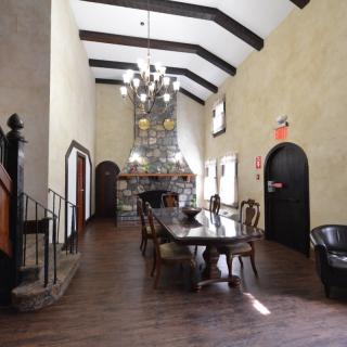 A spacious dining room with a long table, high ceiling, and a grand chandelier.