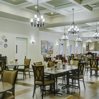 A spacious dining room with elegant chandeliers and neatly arranged tables and chairs.