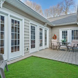 A cozy residential patio with artificial grass and outdoor seating, surrounded by elegant French doors.