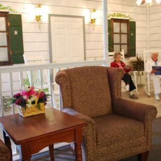 A cozy seating area with an armchair, table, and flowers, with people in the background.