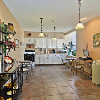 A modern kitchen and dining area with white cabinets, tiled flooring, and contemporary lighting.