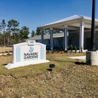 A modern building with a sign reading 'Nuggets Gardens' set against a clear blue sky.