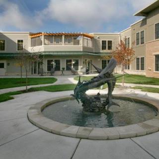 A courtyard featuring a fountain with a sculpture, surrounded by a building.