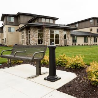 A modern building with a landscaped garden and bench in the foreground.