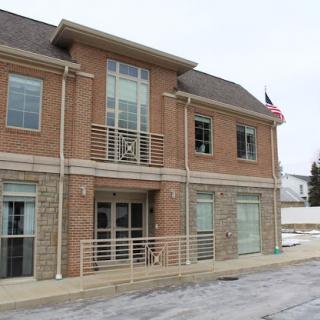 A two-story brick building featuring large windows and an American flag.