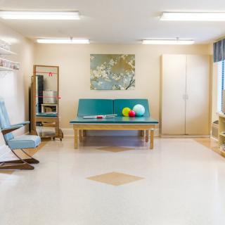 A bright and minimalist therapy room with a couch, table, and exercise equipment.
