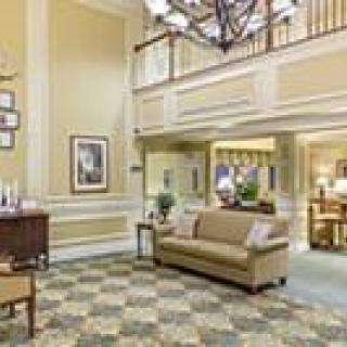 A cozy lobby with a sofa, decorative carpet, and chandelier.