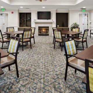 A cozy dining area with multiple tables and chairs, featuring a fireplace and television.