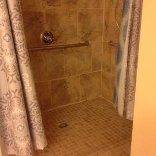 A tiled shower area with patterned curtains.