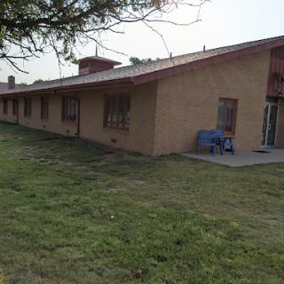 A view of a single-story building surrounded by grass.