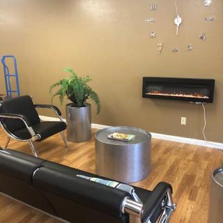 A modern waiting room with sleek furniture and a wall-mounted fireplace.