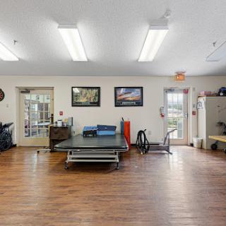 A spacious rehabilitation room equipped with various exercise tools and ample natural light.