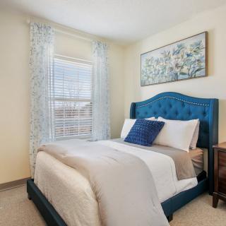 A cozy bedroom with a blue headboard and decorative artwork.