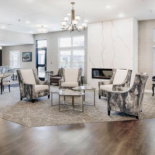 A modern living room with stylish chairs, a central table, and a sleek fireplace under bright lighting.